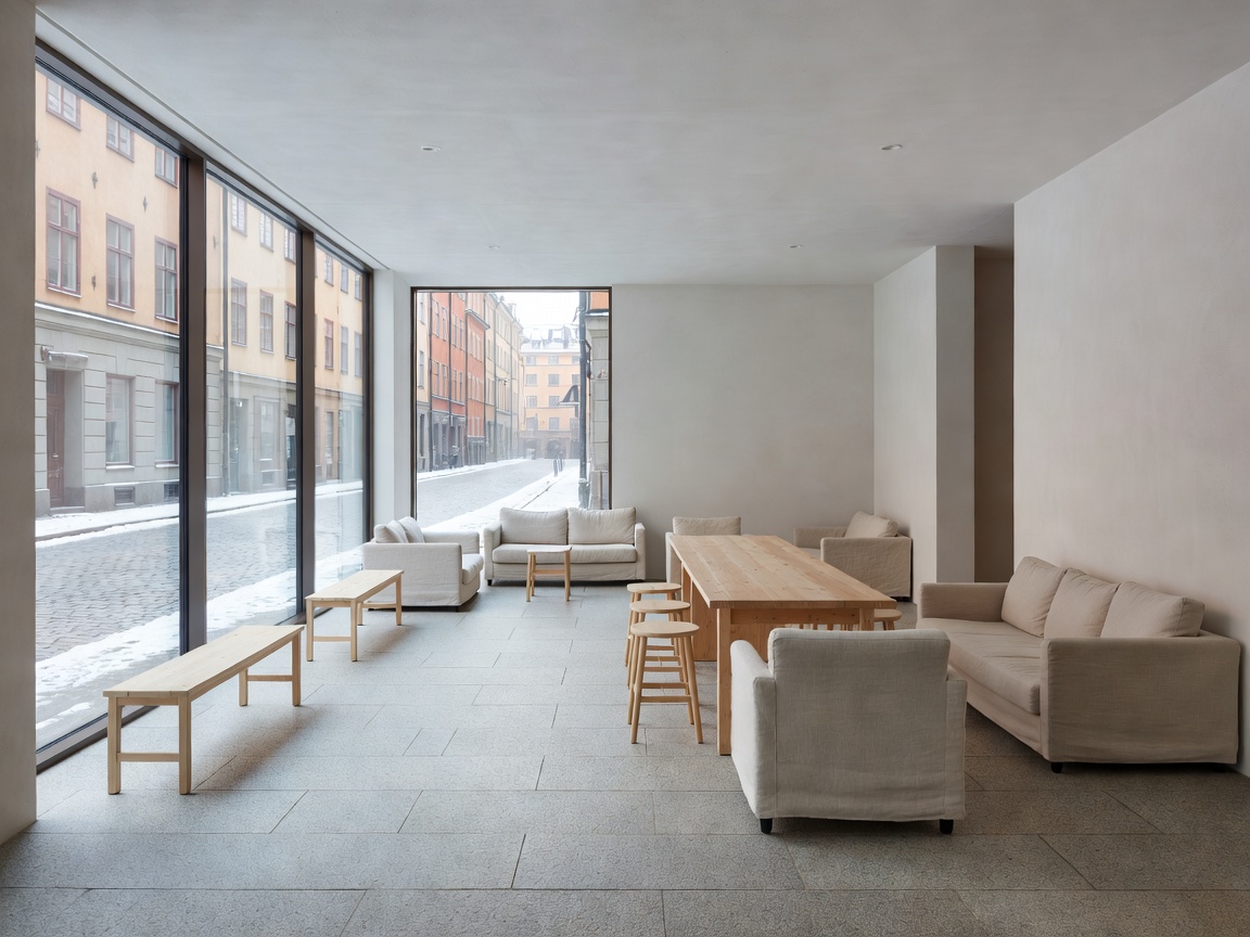 Scandinavian minimalist hostel lobby with floor-to-ceiling glass and stone floors in Stockholm